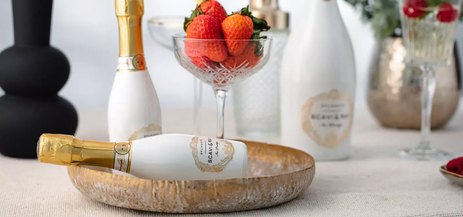 Ein Tisch der mit scavi & ray prosecco Ice Prestige Flaschen gedeckt ist und einem Glas frischer Erdbeeren.